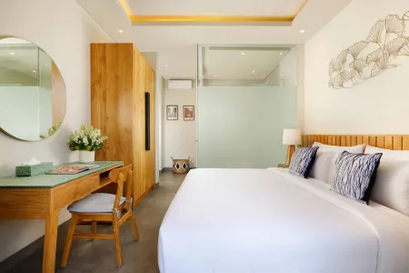 Modern Bali-style bedroom with wooden king bed, desk, round mirror, and tropical leaf wall art.