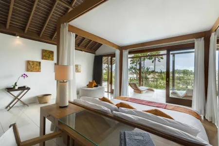 Luxurious Balinese villa bedroom with wooden canopy bed, tropical balcony view, and orchid decor.