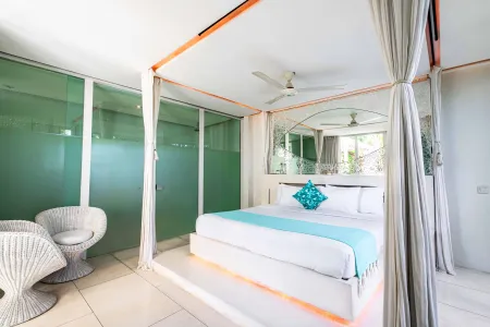 Luxurious tropical bedroom with white canopy bed, teal bedding, wicker armchair, and frosted green glass walls.