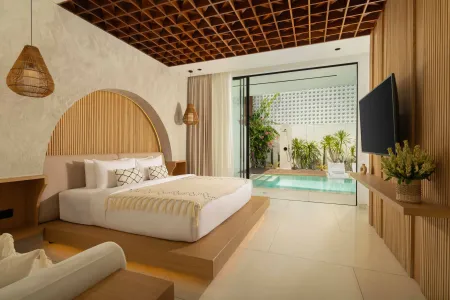 Elegant tropical bedroom with wooden accents, king bed, and sliding doors to private plunge pool.