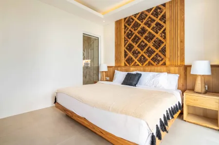 Spacious modern bedroom with wooden lattice headboard, king-size bed, nightstands, and glass door to balcony.