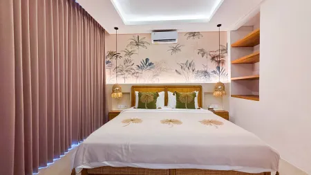 Serene tropical bedroom interior with palm-leaf wallpaper, rattan pendant lights, green leaf pillows on a white bed, and pink sheer curtains.