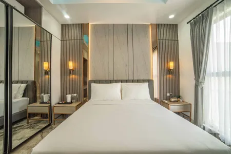 Modern bedroom interior with a king-size bed, gray slatted headboard wall, wall sconces, nightstands, and sheer window curtains.