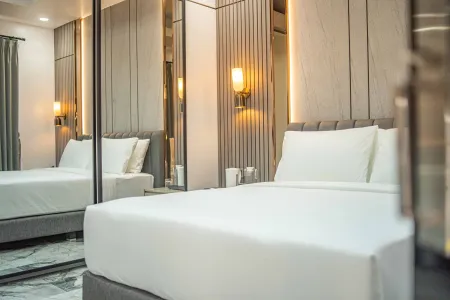 Elegant modern bedroom interior with plush white bed, mirrored wardrobe, wood-panel accents, and soft wall sconce lighting.