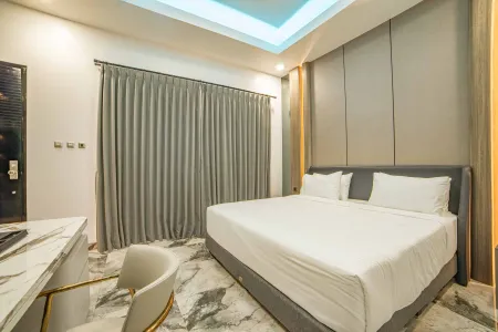 Modern luxury bedroom with king-sized bed, marble desk and chair, gray curtains, and blue LED ceiling lights.