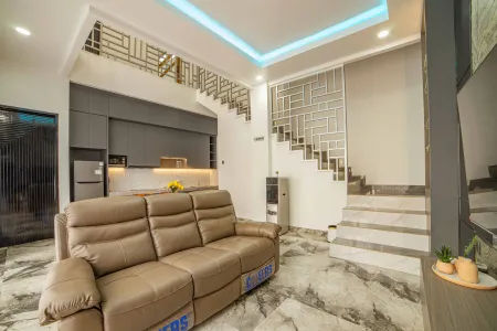 Modern living room with tan leather sofa, open kitchen, wooden staircase, and blue LED ceiling lights in contemporary home interior. - Bali Villas