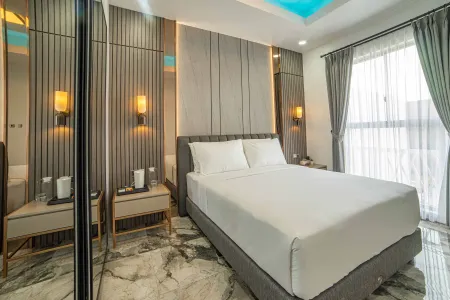 Modern luxury hotel bedroom with king-sized bed, gray paneled walls, marble floor, and blue-lit ceiling. - Bali Villas