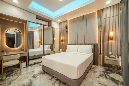 Modern luxury bedroom featuring a king-sized bed with white linens, mirrored vanity, LED accents, and marble flooring.