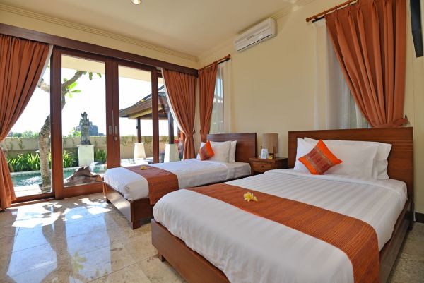 Luxurious Balinese villa bedroom with twin beds, orange curtains, and tropical garden view through sliding doors.