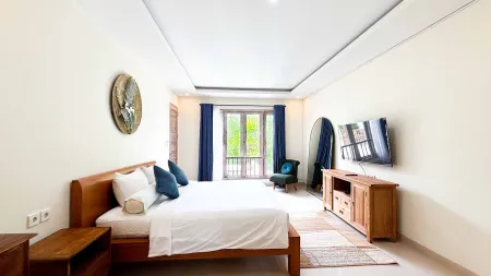 Spacious modern bedroom with wooden bed, blue accents, armchair, and garden-view balcony.