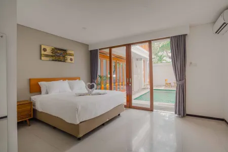 Modern tropical bedroom with king-size bed and sliding glass doors overlooking a private pool.