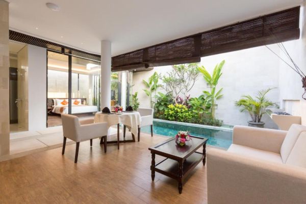 Luxurious Balinese villa interior with private plunge pool, tropical garden, wooden furniture, and bedroom suite.