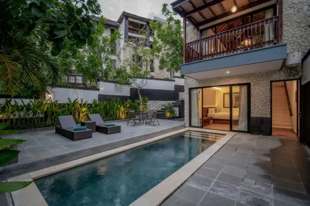Luxurious tropical villa with private infinity pool, outdoor lounge chairs, and open bedroom doors amid lush greenery.