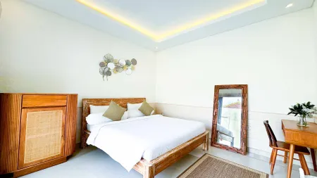 Modern tropical bedroom with wooden bed, large wall mirror, rattan cabinet, desk, and ambient LED lighting.