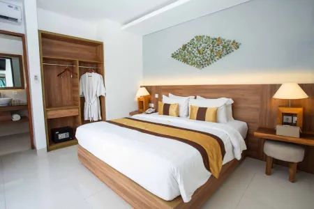Luxurious wooden Balinese bedroom with king bed, white linens, hanging robe, and tropical leaf wall art.