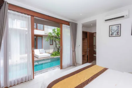 Luxurious Bali villa bedroom with open sliding doors revealing a private infinity pool and chaise lounge.