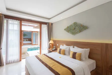 Luxurious Balinese bedroom with king bed, yellow accents, and open sliding doors to a private infinity pool.