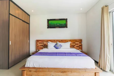 Serene wooden bed with white bedding and purple accents in a modern tropical bedroom featuring green wall art and sliding glass doors.