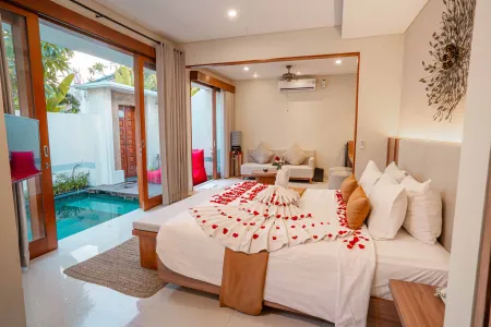 Luxurious Bali villa bedroom with private plunge pool, rose petal-adorned king bed, and tropical wooden accents.