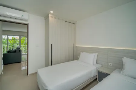 Modern minimalist hotel bedroom with white twin beds, built-in wardrobe, and balcony view of tropical palm trees.