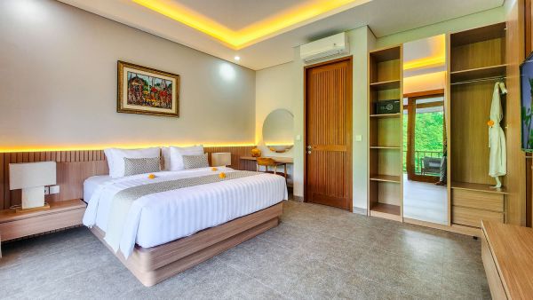 Spacious Balinese villa bedroom with wooden king bed, vanity mirror, open wardrobe, and lush garden view balcony. - Bali Villas