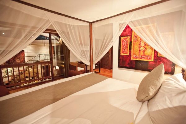 Luxurious tropical bedroom featuring a white canopy bed, sheer curtains, balcony view, and vibrant red abstract wall art.