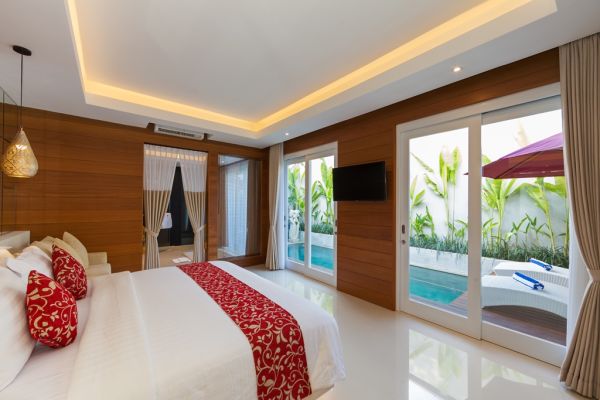 Luxurious Balinese bedroom with king bed, wooden accents, and private poolside view through sliding doors.