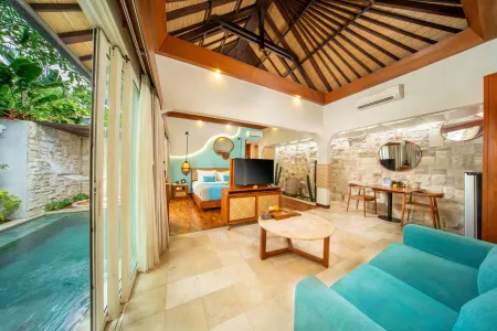 Spacious luxury Balinese villa bedroom with private plunge pool, king bed, teal sofa, and tropical wooden architecture.