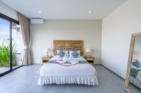 Luxurious tropical bedroom with king bed, rose petals, swan towels, and sliding doors to lush garden.
