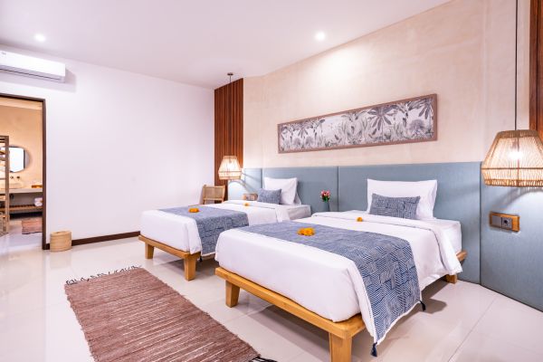 Cozy Balinese twin bedroom with blue batik bed runners, wooden headboards, and tropical wall art.