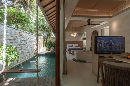 Luxurious open-plan Bali villa bedroom with private plunge pool, tropical plants, wooden swing, and modern blue bedding.