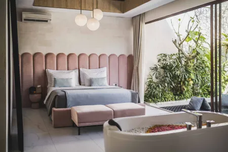 Luxurious modern bedroom with pink tufted headboard bed, open garden views, and petal-filled freestanding bathtub.