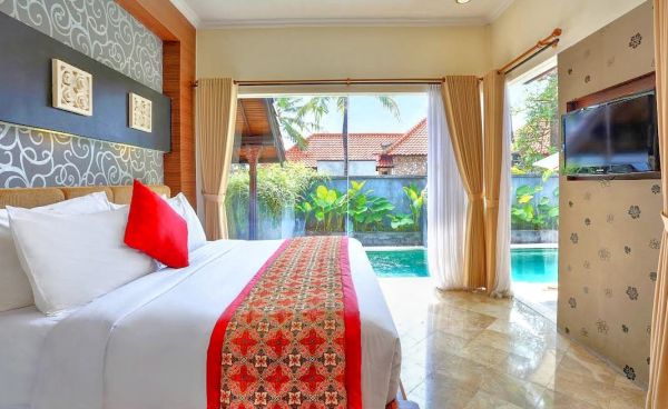 Luxurious Balinese villa bedroom with king bed, red accents, and sliding doors to private infinity pool. - Bali Villas