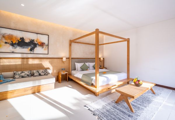 Luxurious Balinese bedroom with wooden four-poster bed, neutral tones, abstract wall art, and tropical fruit accents.