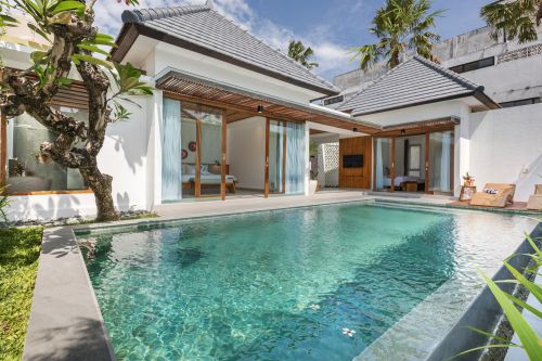Modern Balinese villa with private infinity pool, open sliding doors to bedroom, and lush tropical garden.