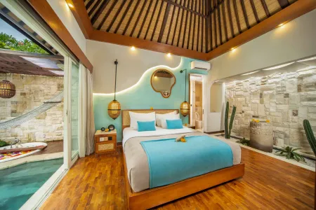 Luxurious Balinese villa bedroom with king bed, private plunge pool, stone walls, and tropical greenery.