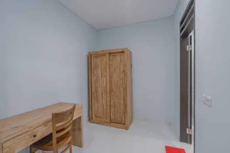 Minimalist bedroom with light blue walls, wooden desk and chair, and tall sliding-door wardrobe.