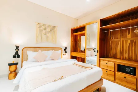 Cozy tropical bedroom with wooden bed, pink bedding, rattan accents, and mirrored wardrobe.