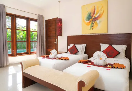 Luxurious Balinese bedroom with twin beds adorned in red pillows and towel swans, poolside view through large windows, and vibrant abstract wall art.
