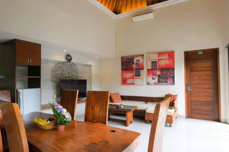 Spacious Balinese villa living room with wooden dining table, lounge seating, abstract red wall art, and tropical decor. - Bali Villas