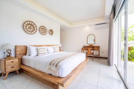 Spacious tropical bedroom with wooden bed, woven wall baskets, vanity mirror, and sliding doors to garden view.