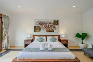 Luxurious Balinese bedroom with wooden platform bed, teal accents, abstract wall art, and potted plants.